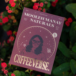 A pack of Mooleh Manay Naturals coffee placed on a surface with red and yellow flowers around it.