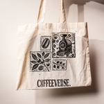 Beige Coffeeverse tote bag with black illustrations of coffee beans, plants, and a coffee roaster printed on the front.