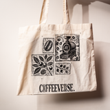 Beige Coffeeverse tote bag with black illustrations of coffee beans, plants, and a coffee roaster printed on the front.